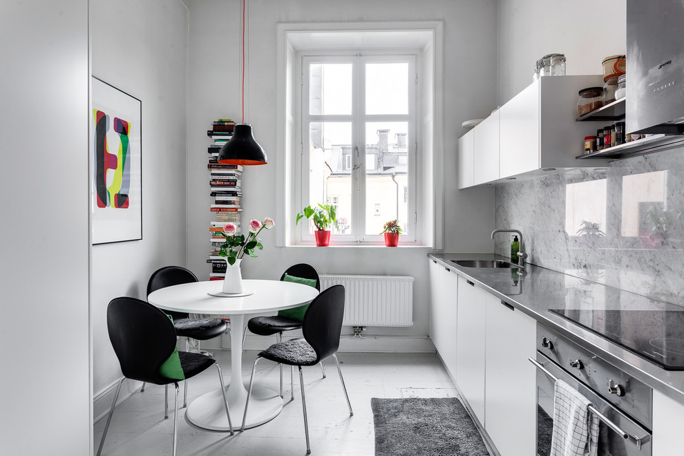 Inspiration for a mid-sized scandinavian single-wall eat-in kitchen in Stockholm with flat-panel cabinets, stainless steel benchtops, grey splashback, stainless steel appliances, painted wood floors, no island and an undermount sink.