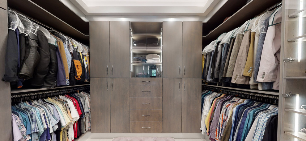 Imagen de armario vestidor de hombre minimalista grande con armarios con paneles lisos, puertas de armario grises, suelo de baldosas de porcelana, suelo beige y casetón