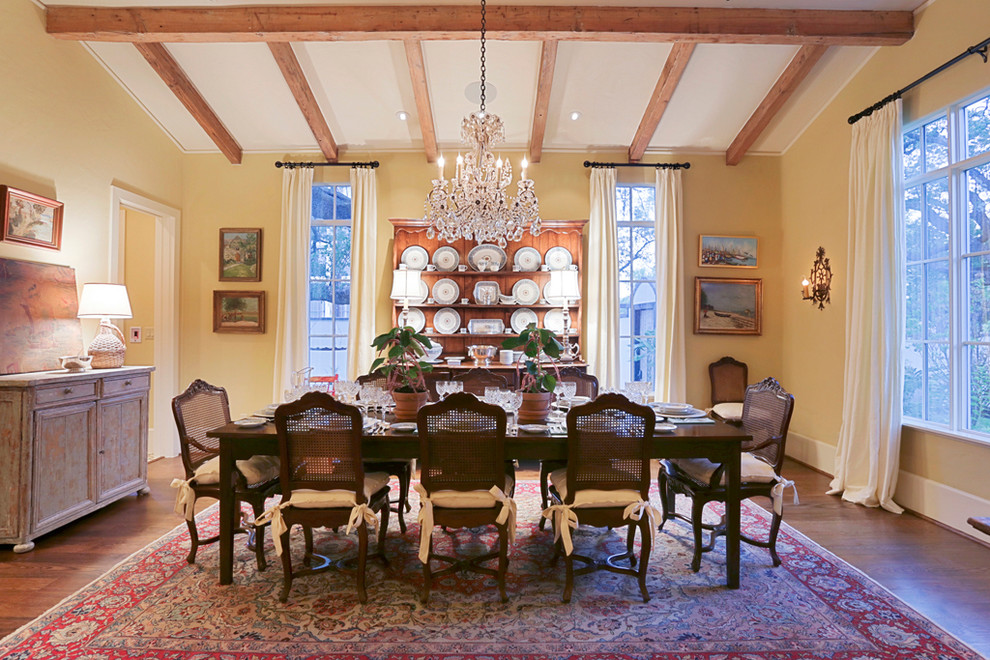 Photo of a large traditional separate dining room in Houston with yellow walls and dark hardwood floors.