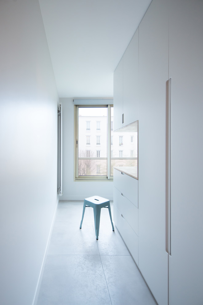 Photo of a mid-sized scandinavian single-wall utility room in Paris with beaded inset cabinets, grey cabinets, concrete floors and brown benchtop.