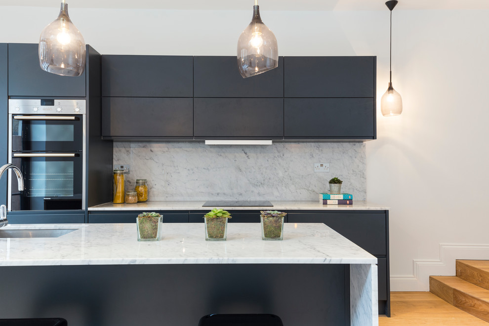 Photo of a mid-sized modern galley eat-in kitchen in London with grey cabinets and with island.