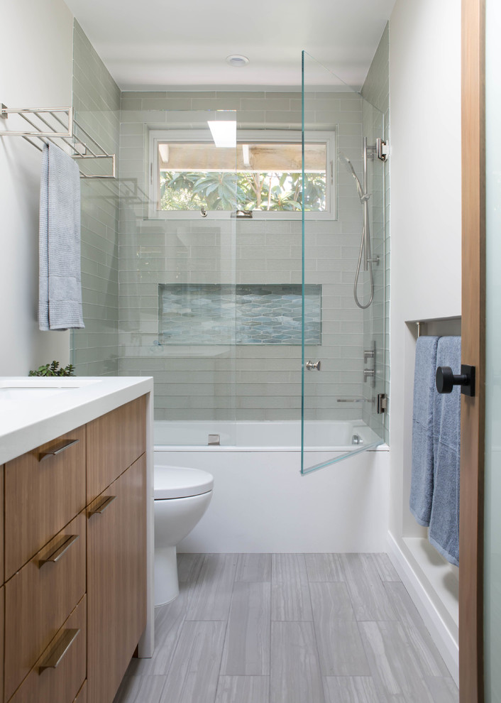Trendy 3/4 glass tile porcelain tile and gray floor bathroom photo in Los Angeles with flat-panel cabinets, medium tone wood cabinets, a one-piece toilet, an undermount sink, quartz countertops, a hinged shower door and white countertops