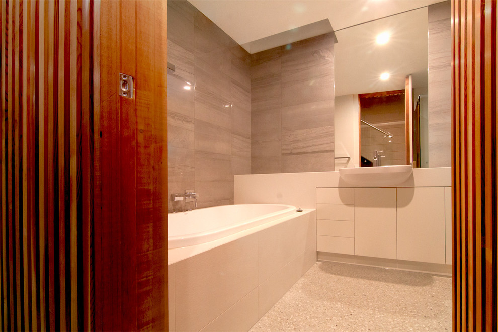 Photo of a small contemporary kids wet room bathroom in Other with white cabinets, gray tile, stone tile, concrete floors, engineered quartz benchtops and beige floor.