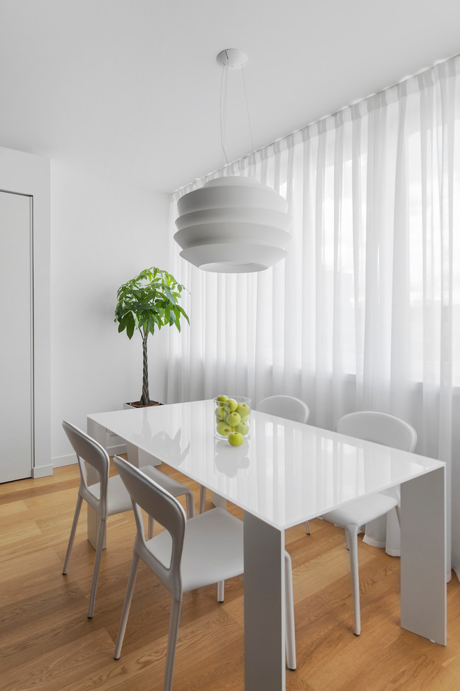 Contemporary dining room in Moscow with white walls and light hardwood floors.