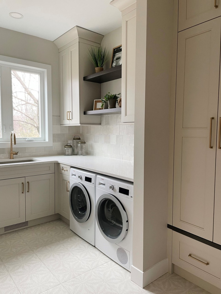 Photo of a medium sized classic l-shaped utility room in Minneapolis with a submerged sink, shaker cabinets, beige cabinets, marble worktops, grey splashback, mosaic tiled splashback, beige walls, ceramic flooring, a side by side washer and dryer, multi-coloured floors and white worktops.