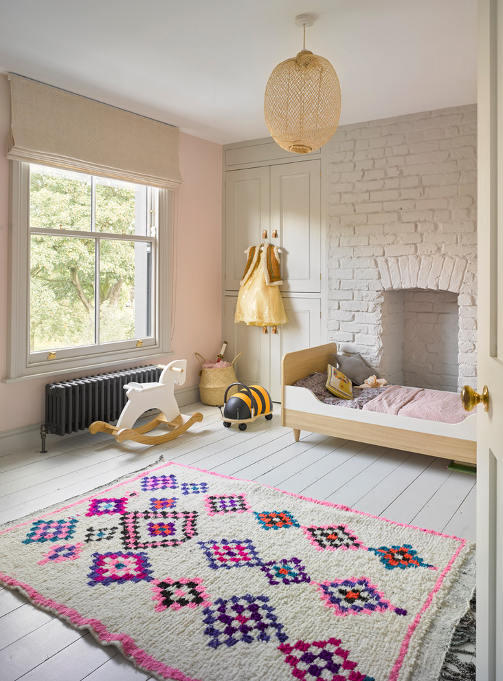 Scandinavian kids' room in London with pink walls, painted wood floors and white floor for girls.