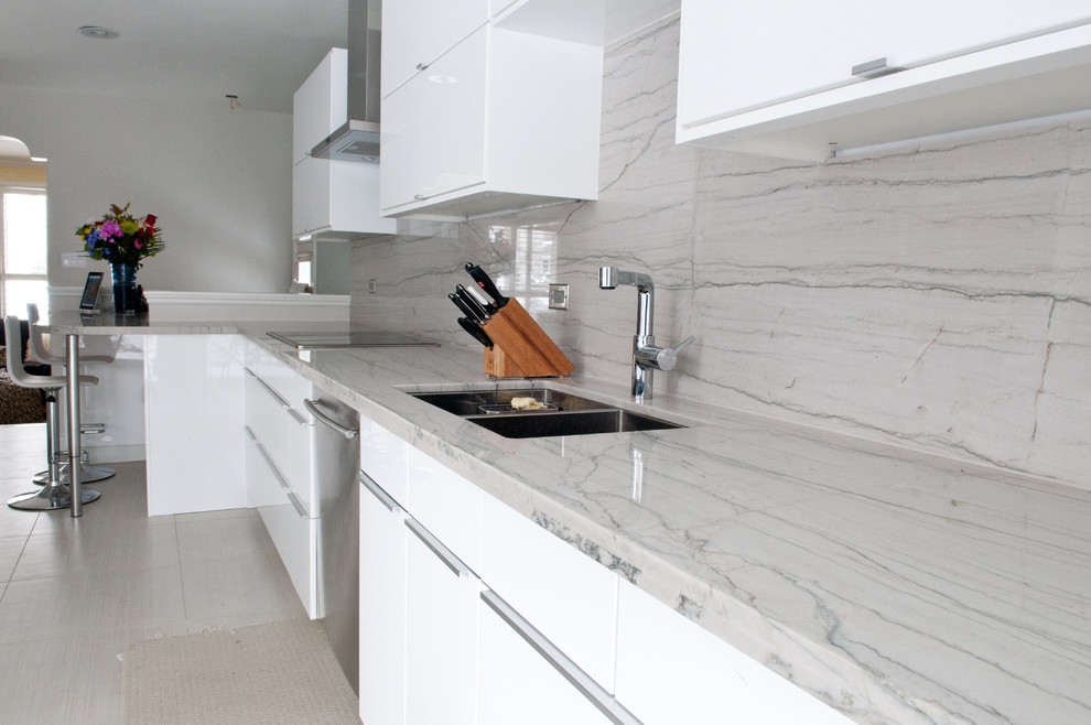 Design ideas for a large contemporary galley open plan kitchen in Toronto with a double-bowl sink, flat-panel cabinets, white cabinets, quartzite benchtops, grey splashback, stone slab splashback, stainless steel appliances, porcelain floors, no island, beige floor and white benchtop.