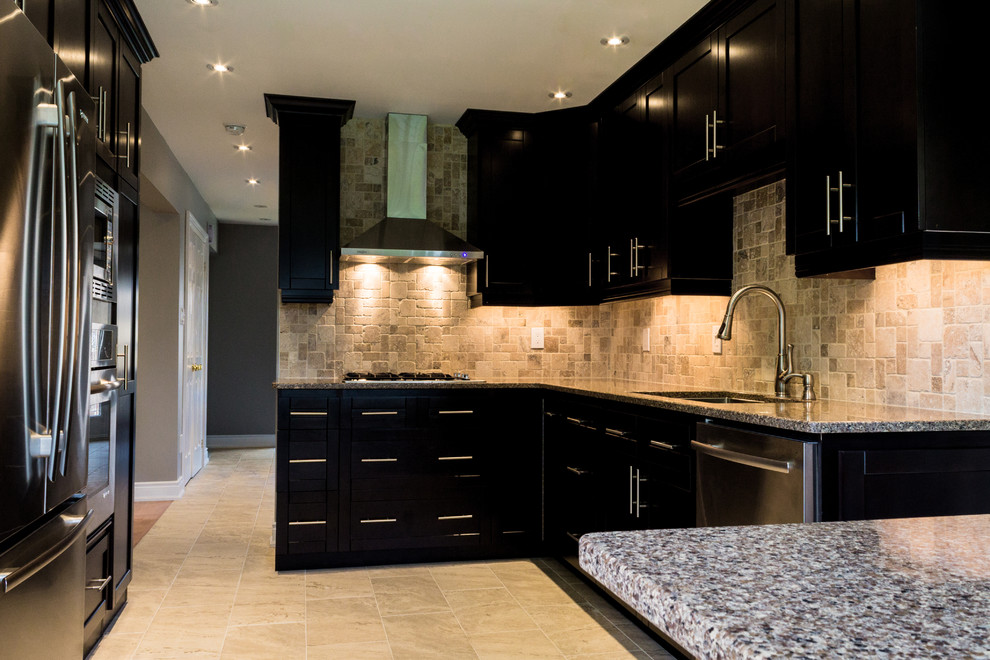 Small transitional l-shaped separate kitchen in Toronto with beige splashback, stone slab splashback, stainless steel appliances, with island, an undermount sink, shaker cabinets, black cabinets, granite benchtops and limestone floors.