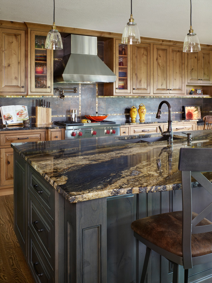 Example of a large mountain style l-shaped medium tone wood floor open concept kitchen design in Denver with a double-bowl sink, raised-panel cabinets, light wood cabinets, granite countertops, brown backsplash, porcelain backsplash, stainless steel appliances and an island