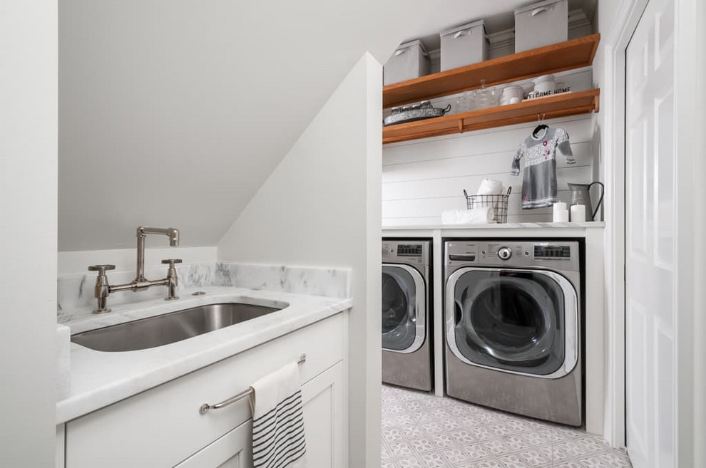 Inspiration for a mid-sized traditional single-wall utility room in Atlanta with a single-bowl sink, shaker cabinets, white cabinets, marble benchtops, grey walls, ceramic floors, a side-by-side washer and dryer, grey floor and white benchtop.