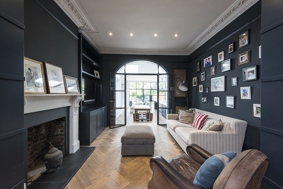 Inspiration for a traditional enclosed living room in London with black walls, medium hardwood floors and a standard fireplace.