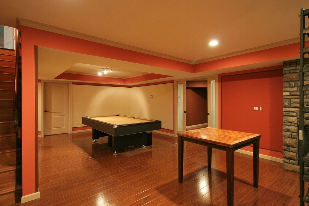 Basement - mid-sized transitional underground medium tone wood floor and brown floor basement idea in Vancouver with orange walls, a standard fireplace and a stone fireplace