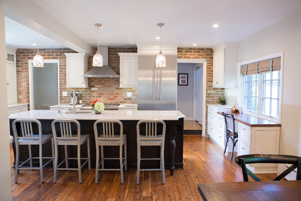 Eat-in kitchen - large transitional medium tone wood floor eat-in kitchen idea with an undermount sink, recessed-panel cabinets, black cabinets, quartz countertops, brick backsplash, stainless steel appliances and an island