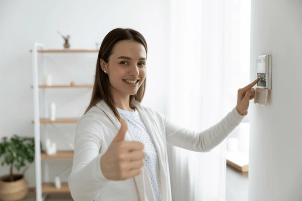 smiling young woman checking alarm system is working
