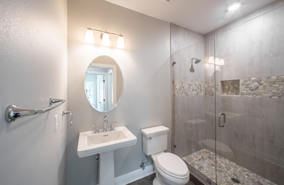 Inspiration for a mid-sized timeless 3/4 multicolored tile and porcelain tile porcelain tile, gray floor and single-sink alcove shower remodel with a one-piece toilet, gray walls, a pedestal sink, a hinged shower door and a niche