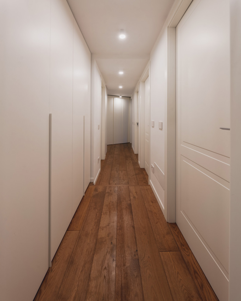 Idéer för en mellanstor modern hall, med vita väggar, mörkt trägolv och brunt golv