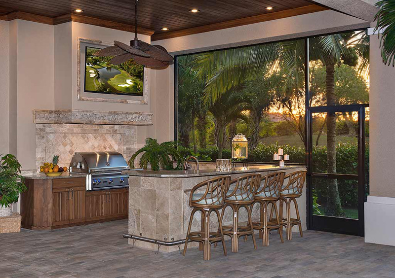 This is an example of a large mediterranean backyard patio in Miami with an outdoor kitchen, natural stone pavers and a roof extension.