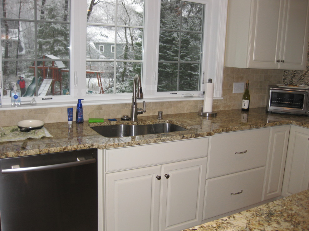 Example of a transitional l-shaped light wood floor eat-in kitchen design in Boston with raised-panel cabinets, white cabinets, granite countertops, beige backsplash, ceramic backsplash, stainless steel appliances, an undermount sink and an island