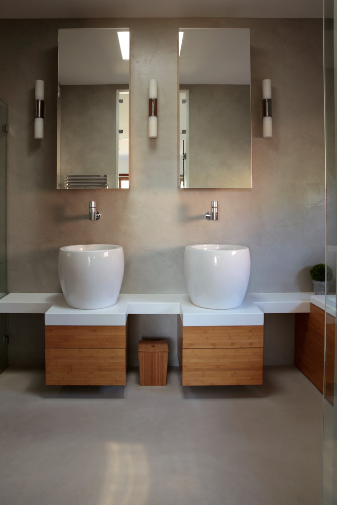 Mid-sized contemporary master bathroom in Grenoble with medium wood cabinets, grey walls, concrete floors and a vessel sink.