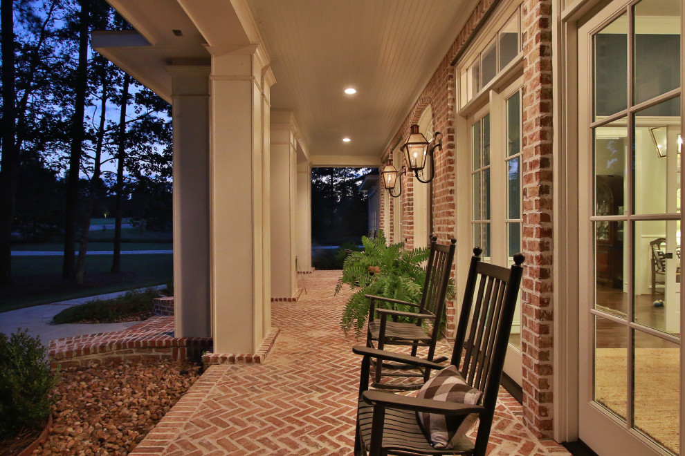 Inspiration for a large traditional front yard verandah in Houston with brick pavers and a roof extension.