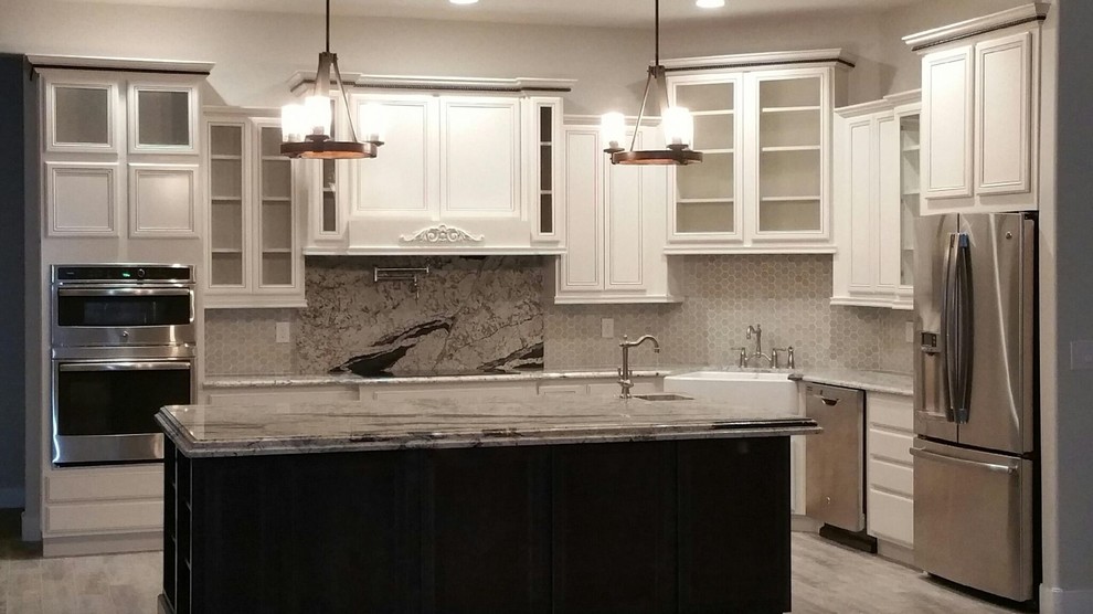 Large transitional l-shaped light wood floor eat-in kitchen photo in Phoenix with a farmhouse sink, raised-panel cabinets, white cabinets, marble countertops, white backsplash, ceramic backsplash, stainless steel appliances and an island