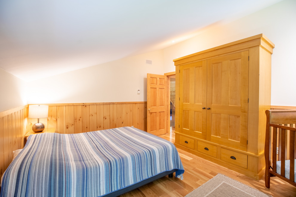 Foto de habitación de invitados rural de tamaño medio sin chimenea con suelo de madera clara, suelo beige, paredes beige, techo inclinado y boiserie
