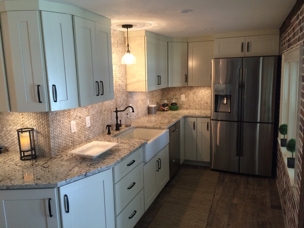 Inspiration for a small transitional l-shaped medium tone wood floor kitchen remodel in Boston with a farmhouse sink, shaker cabinets, white cabinets, granite countertops, beige backsplash, stone tile backsplash, stainless steel appliances and no island