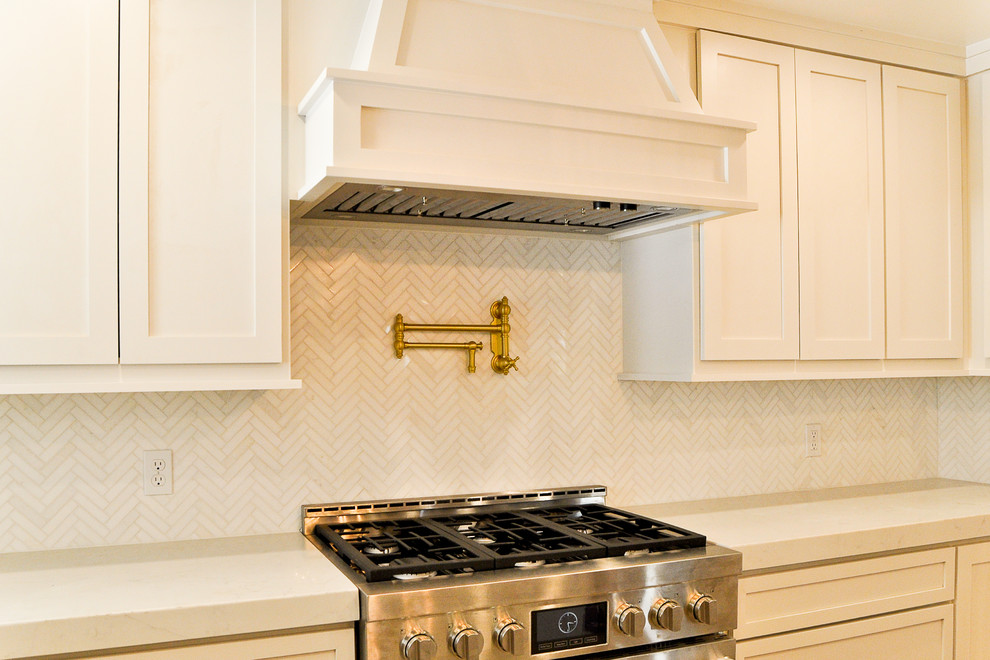Example of a mid-sized transitional kitchen design in New Orleans with shaker cabinets, white cabinets, quartz countertops, white backsplash, marble backsplash, stainless steel appliances and white countertops