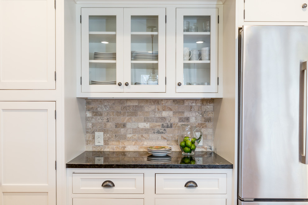 Design ideas for a large country galley eat-in kitchen in New York with an undermount sink, beaded inset cabinets, white cabinets, granite benchtops, beige splashback, stone tile splashback, stainless steel appliances, medium hardwood floors, with island and black benchtop.