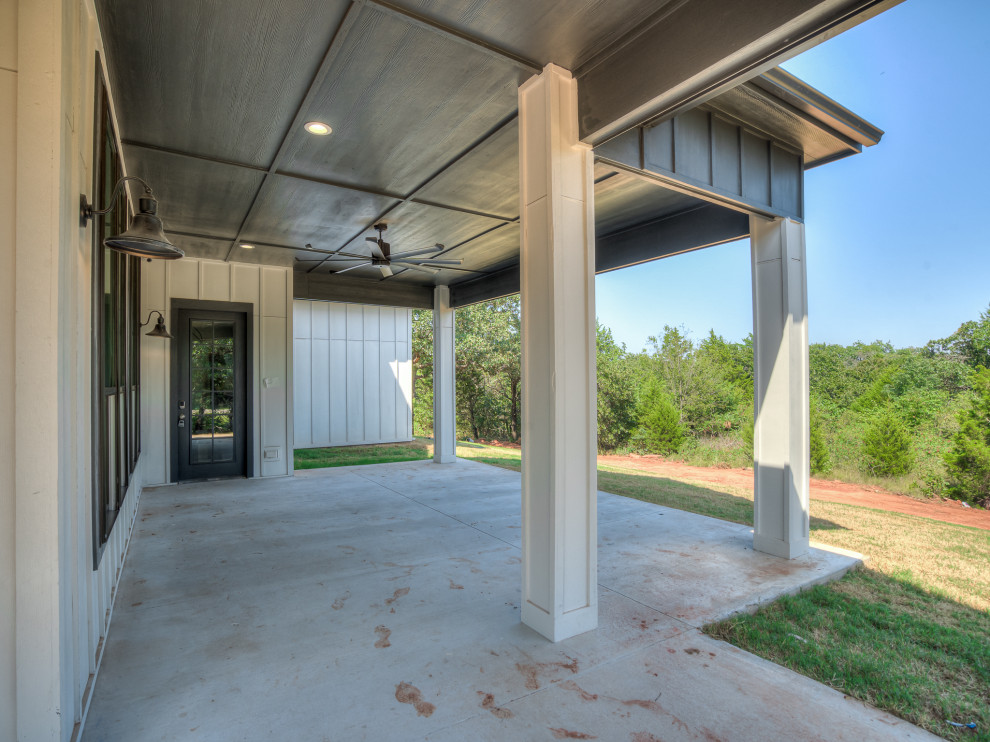 Photo of a large country backyard verandah in Oklahoma City with with columns, concrete slab, a roof extension and mixed railing.