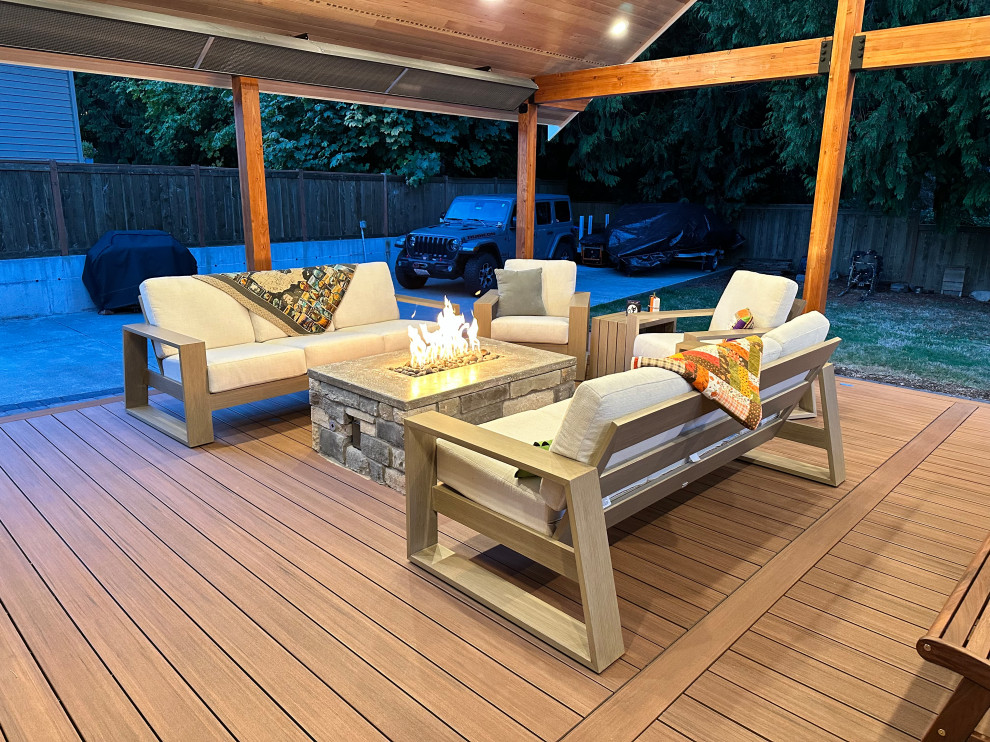 Deck - large craftsman ground level cable railing deck idea in Seattle with a fire pit and a roof extension