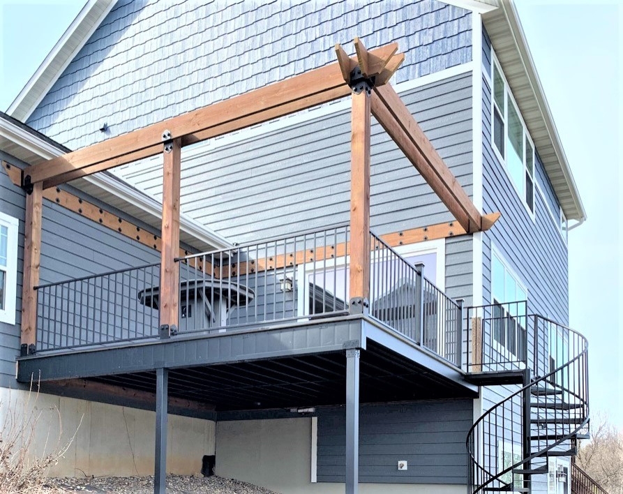 This is an example of a large modern backyard and first floor deck in Minneapolis with a pergola and metal railing.