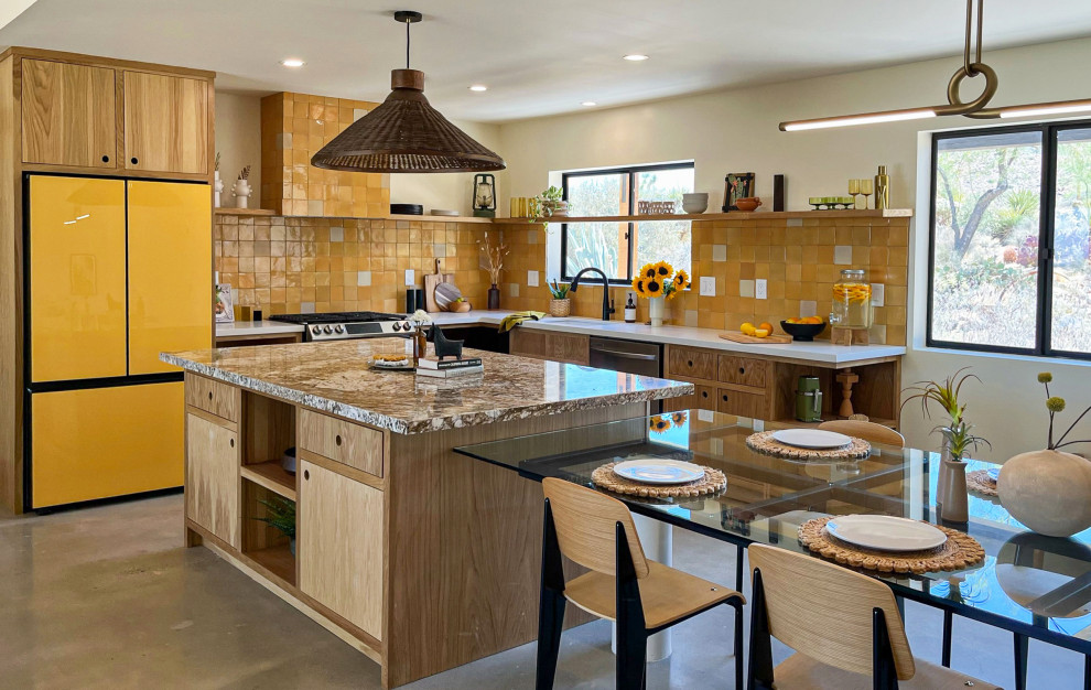 L-shaped kitchen/diner in Los Angeles with a submerged sink, flat-panel cabinets, medium wood cabinets, marble worktops, yellow splashback, terracotta splashback, coloured appliances, concrete flooring, an island, grey floors and brown worktops.