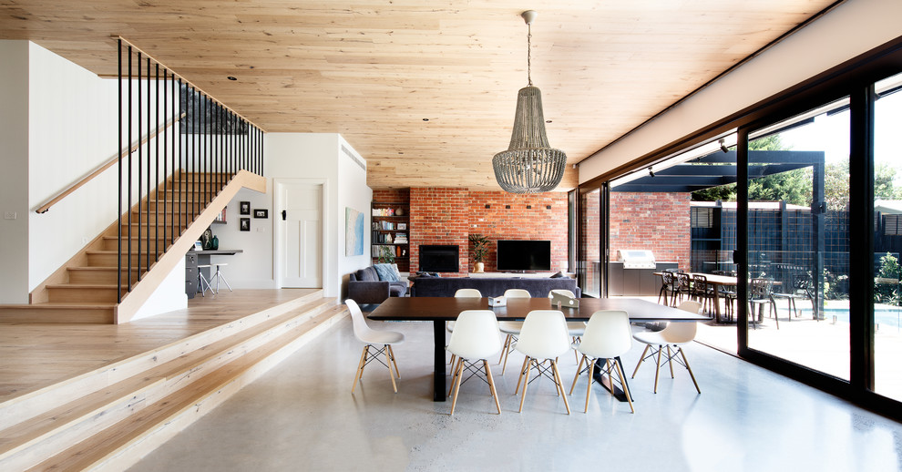 Large contemporary open plan dining in Melbourne with concrete floors, a standard fireplace and a brick fireplace surround.