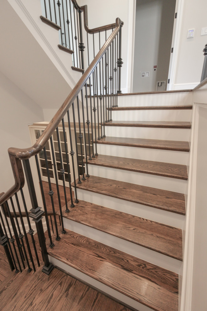 Стильный дизайн: большая лестница на больцах в классическом стиле с деревянными ступенями, крашенными деревянными подступенками и металлическими перилами - последний тренд