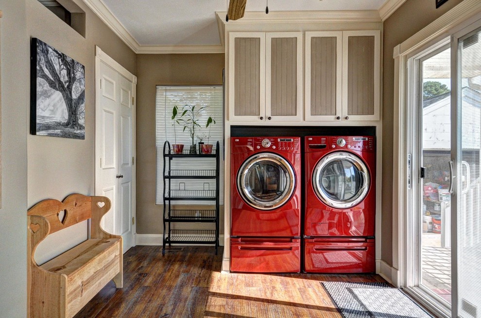 This is an example of a large traditional laundry room in Other with recessed-panel cabinets, beige cabinets, beige walls, dark hardwood floors and a side-by-side washer and dryer.