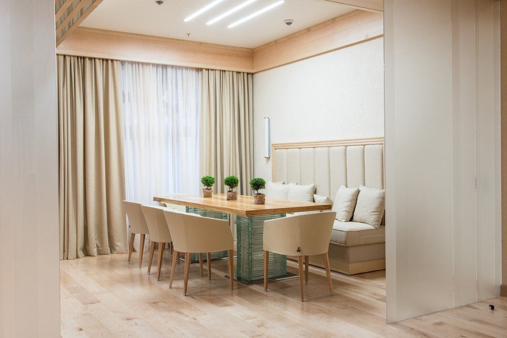 This is an example of a contemporary kitchen/dining combo in Moscow with white walls, light hardwood floors and beige floor.