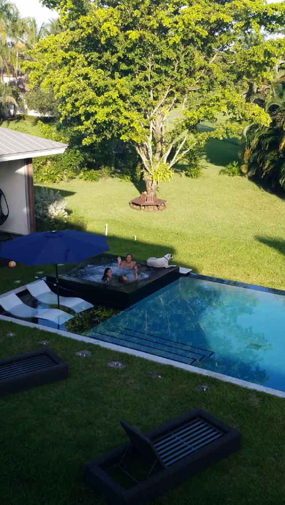 This is an example of a large modern backyard rectangular pool in Miami with a hot tub.