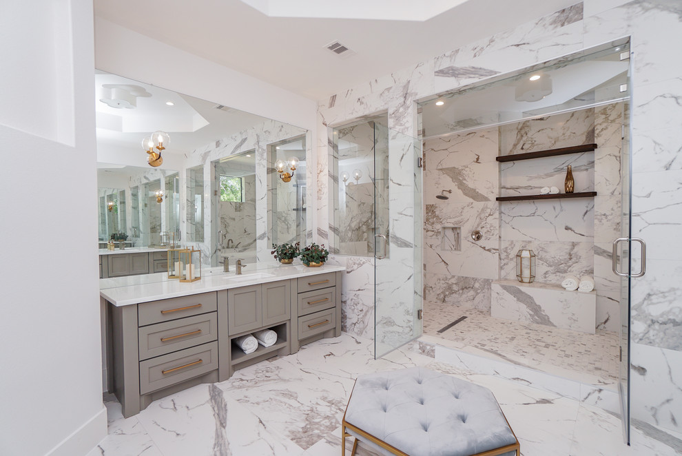 Design ideas for a large transitional master bathroom in Houston with shaker cabinets, grey cabinets, a freestanding tub, a shower/bathtub combo, a two-piece toilet, white tile, porcelain tile, white walls, porcelain floors, an undermount sink, glass benchtops, white floor, a hinged shower door and white benchtops.