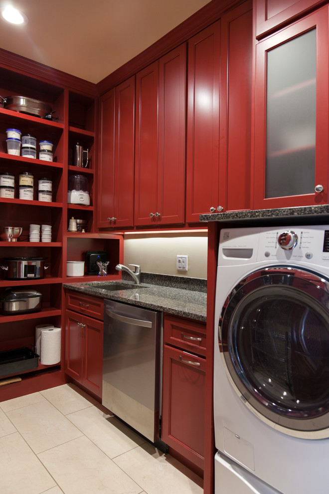Inspiration for a mid-sized transitional u-shaped utility room in St Louis with an undermount sink, red cabinets, granite benchtops, beige walls, porcelain floors, a side-by-side washer and dryer, beige floor, recessed-panel cabinets and black benchtop.