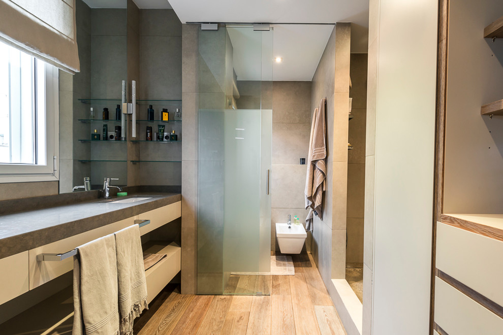 Mid-sized contemporary master bathroom in Madrid with open cabinets, an alcove shower, a bidet, beige walls, light wood cabinets, gray tile, cement tile, light hardwood floors, an undermount sink, concrete benchtops and an enclosed toilet.