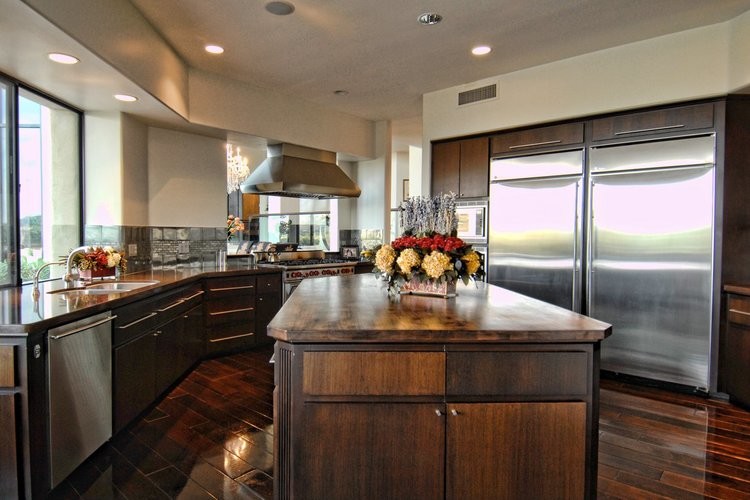 This is an example of an eclectic u-shaped separate kitchen in Phoenix with a double-bowl sink, flat-panel cabinets, dark wood cabinets, concrete benchtops, metallic splashback, metal splashback, stainless steel appliances, dark hardwood floors and with island.