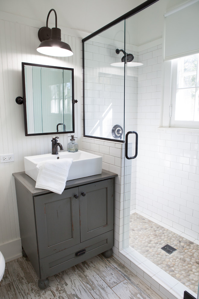 Inspiration for a small country 3/4 bathroom in Chicago with a vessel sink, shaker cabinets, distressed cabinets, a corner shower, white walls, pebble tile, porcelain floors, wood benchtops and white tile.