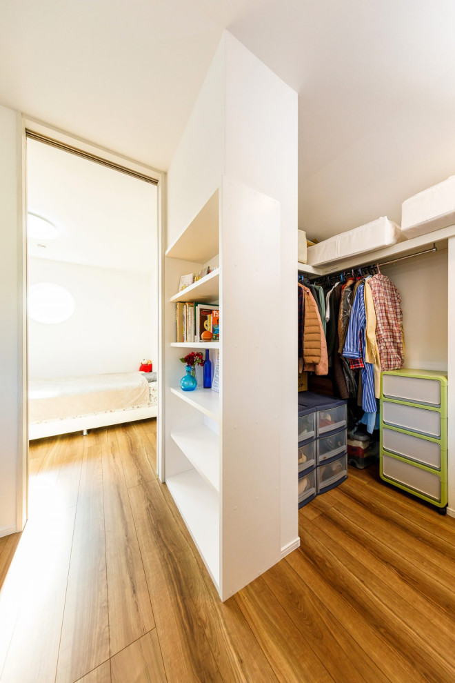 Photo of a medium sized industrial gender neutral walk-in wardrobe in Other with open cabinets, white cabinets, medium hardwood flooring, brown floors and a wallpapered ceiling.