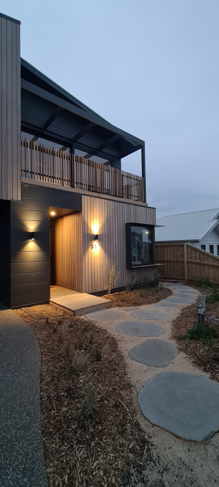 Inspiration pour une grande façade de maison design en bois à un étage avec un toit en métal et un toit noir.
