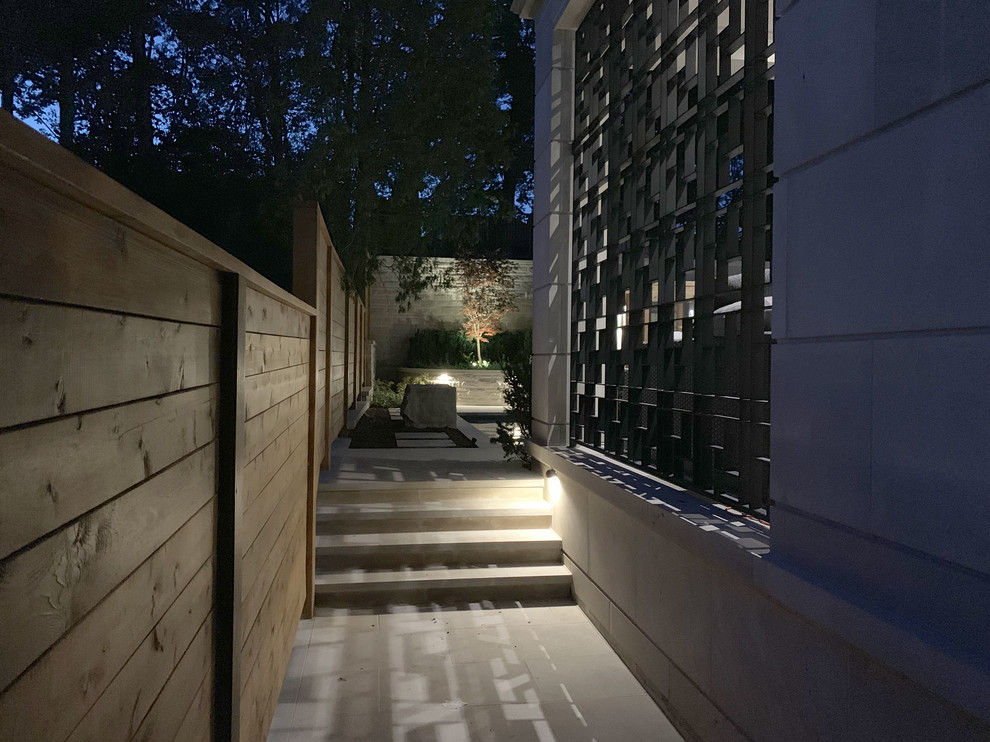 This is an example of a contemporary backyard partial sun garden in Toronto with a retaining wall and natural stone pavers.
