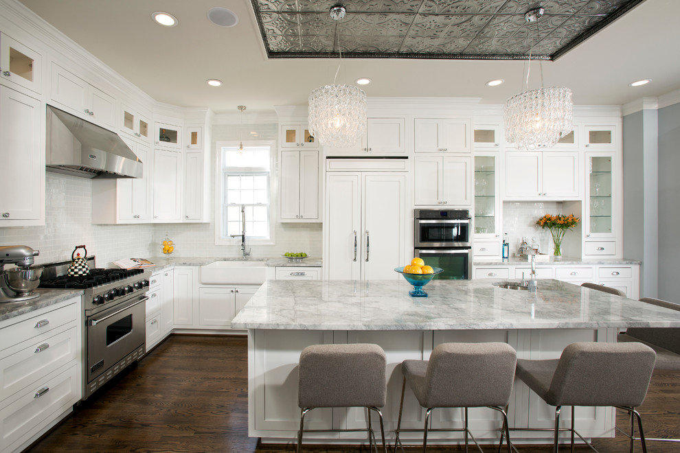 Large transitional l-shaped open plan kitchen in DC Metro with a farmhouse sink, recessed-panel cabinets, white cabinets, white splashback, ceramic splashback, stainless steel appliances, quartzite benchtops, dark hardwood floors and with island.