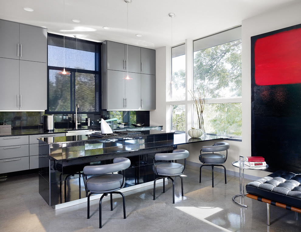 Modern kitchen in Austin with flat-panel cabinets, grey cabinets and black splashback.