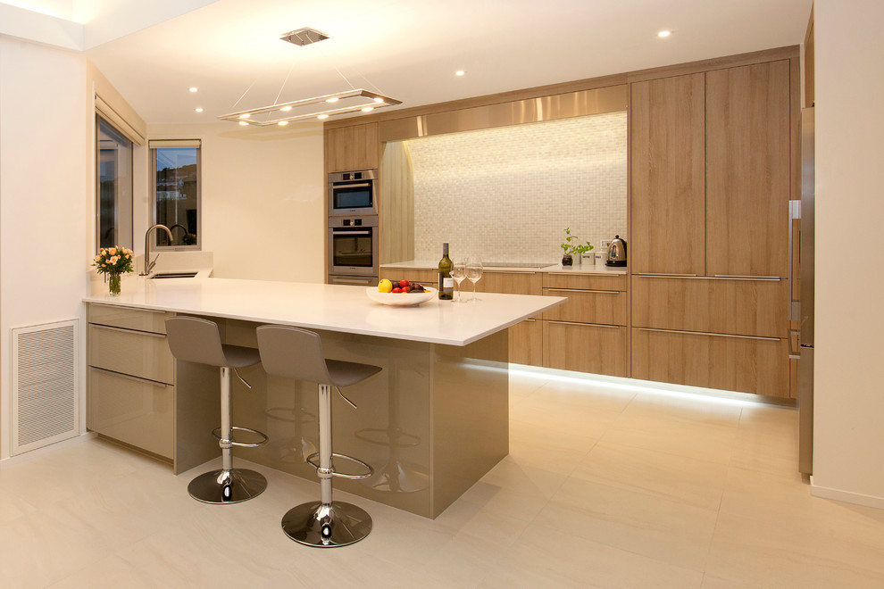 Inspiration for a mid-sized contemporary galley eat-in kitchen in Christchurch with an undermount sink, light wood cabinets, quartz benchtops, white splashback, mosaic tile splashback, stainless steel appliances, ceramic floors, with island, beige floor and white benchtop.