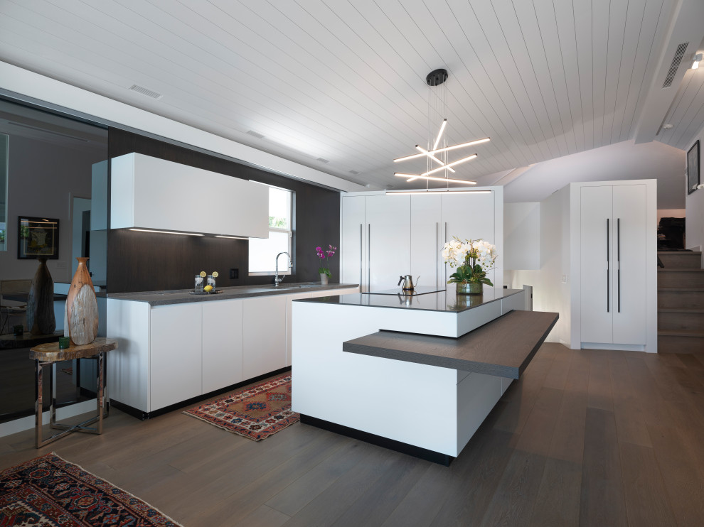 Photo of a mid-sized contemporary l-shaped open plan kitchen in Miami with an undermount sink, flat-panel cabinets, white cabinets, quartz benchtops, brown splashback, timber splashback, panelled appliances, dark hardwood floors, with island, brown floor, brown benchtop and timber.